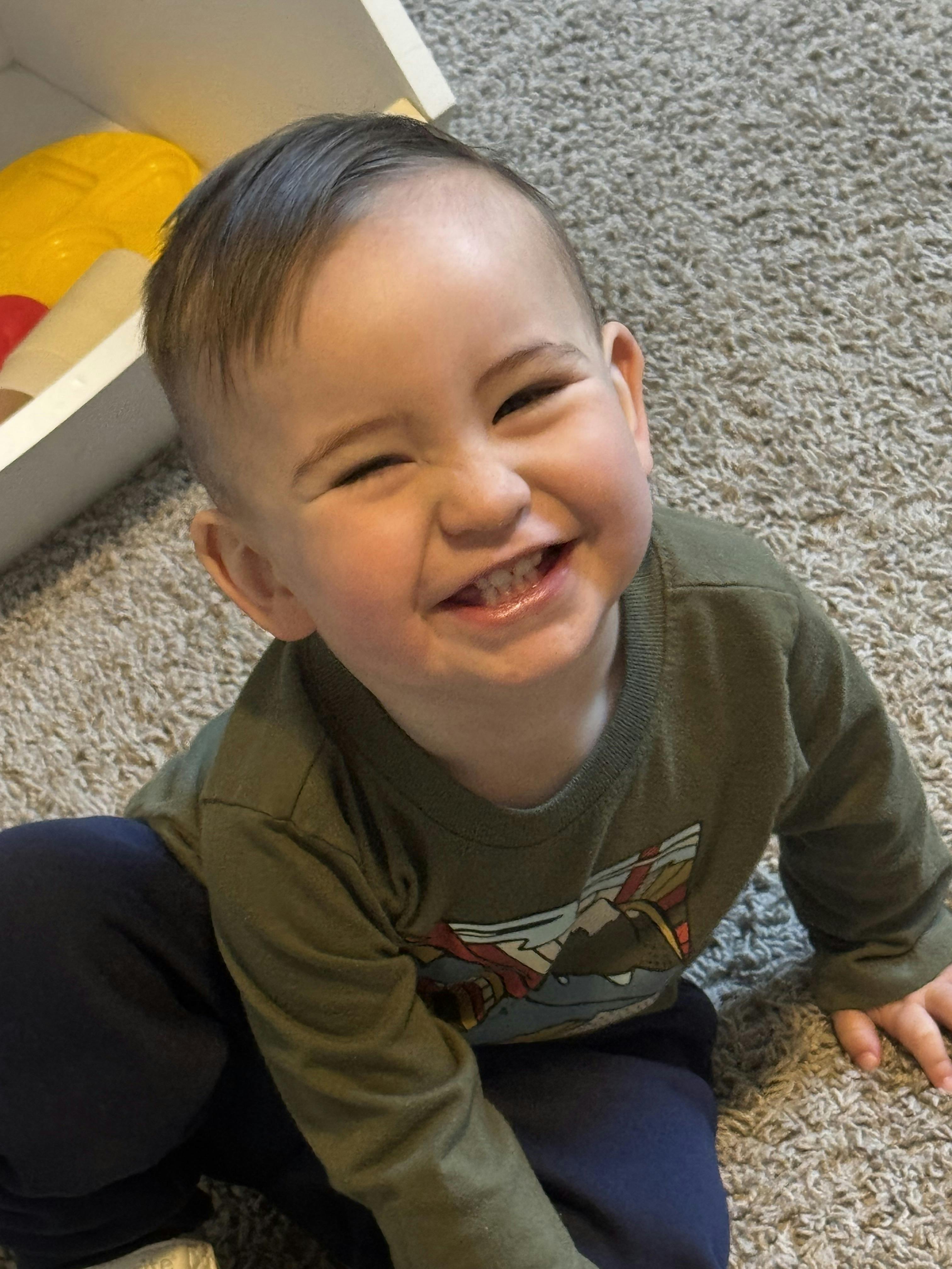 Child smiling on a carpeted floor