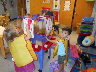 Two children painting at an easel in a classroom