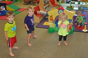 Four children playing in a room with toys
