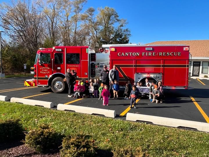 Adults and children standing next to a red fire truck with "CANTON FIRE/RESCUE" on the side