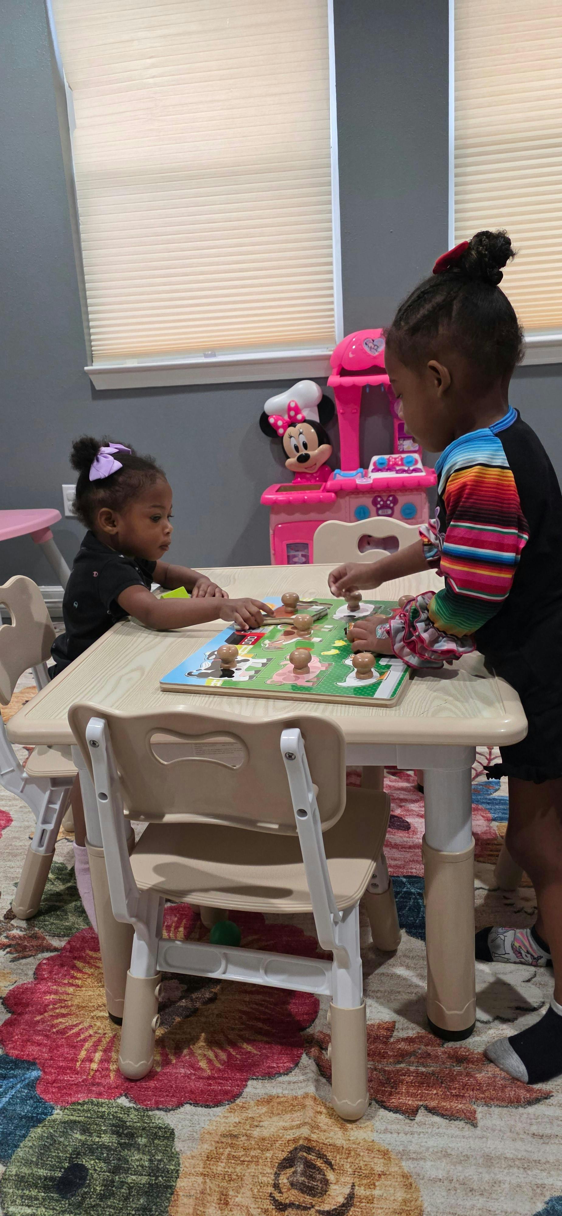 Two children playing with a peg puzzle at a small table