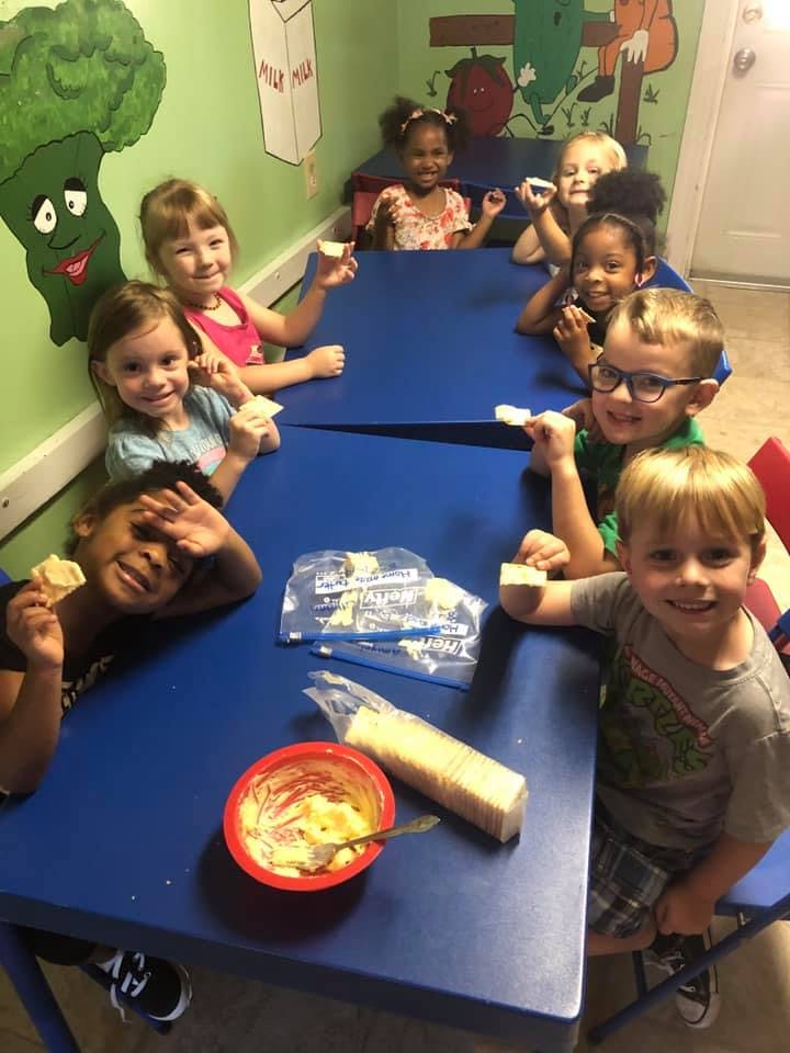 Children sitting at blue tables eating snacks