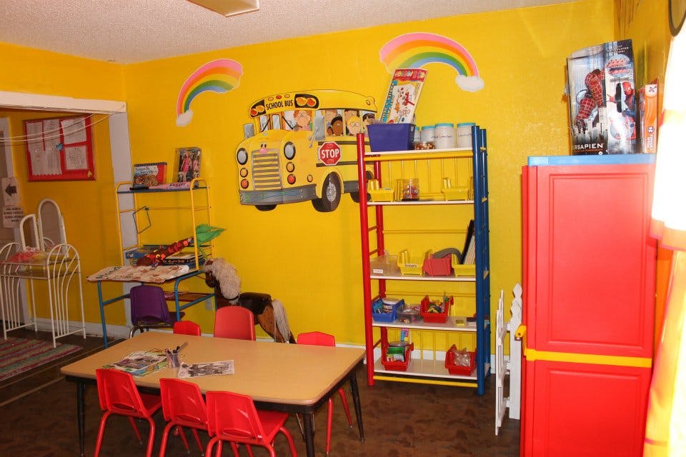 Classroom with tables, chairs, shelves, and a school bus mural