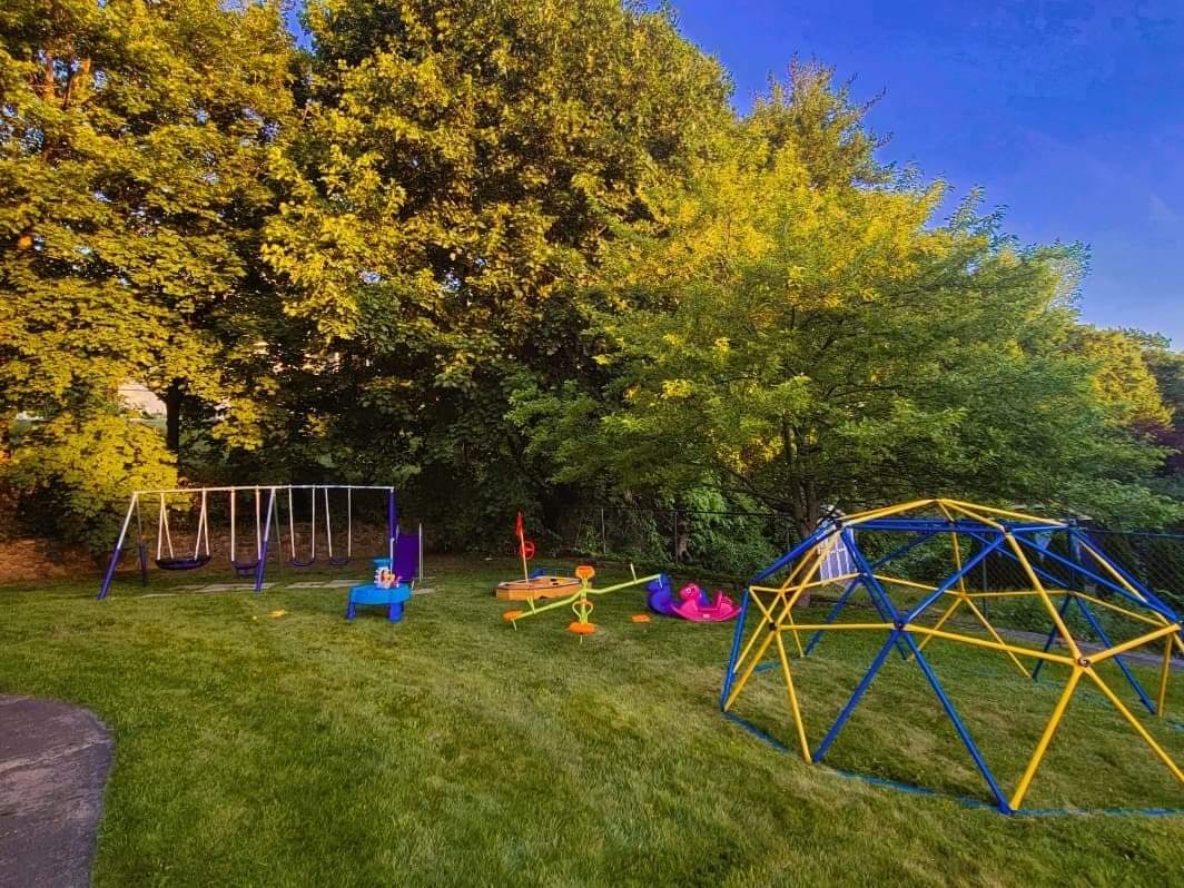 Playground with swings, seesaw, and climbing dome on grass