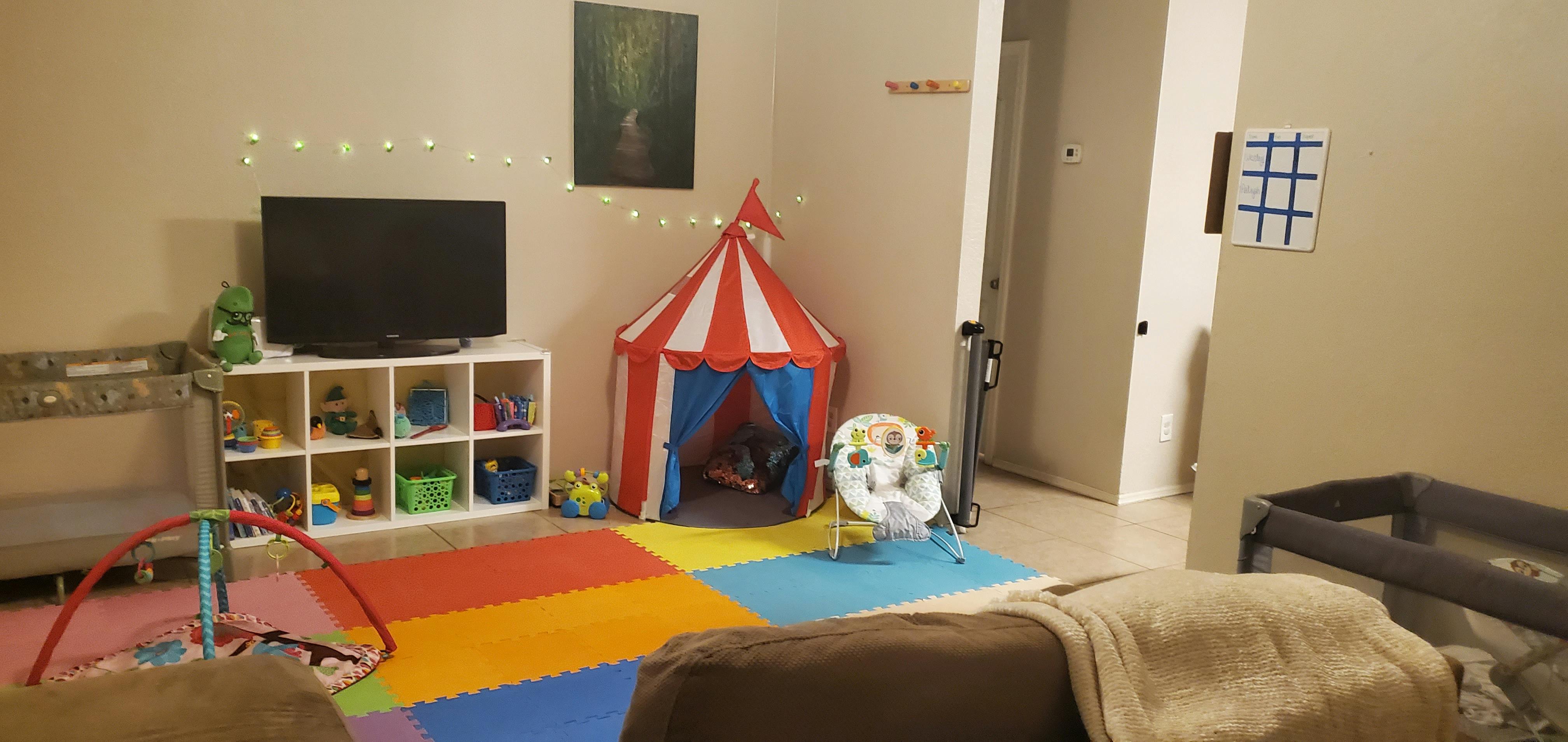 Playroom with a red and white tent, colorful floor mats, and toys