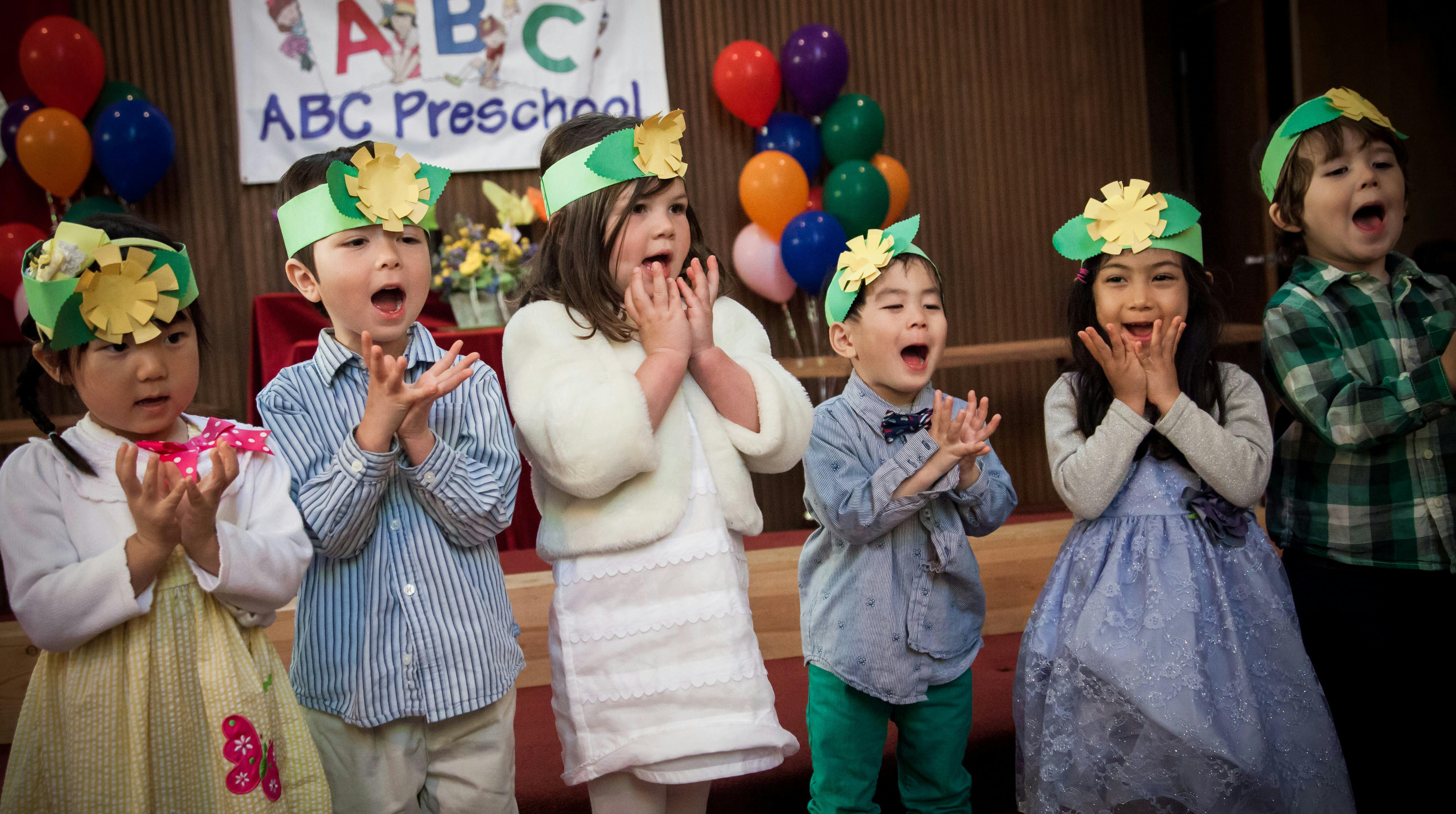 Children in a preschool wearing paper crowns and clapping