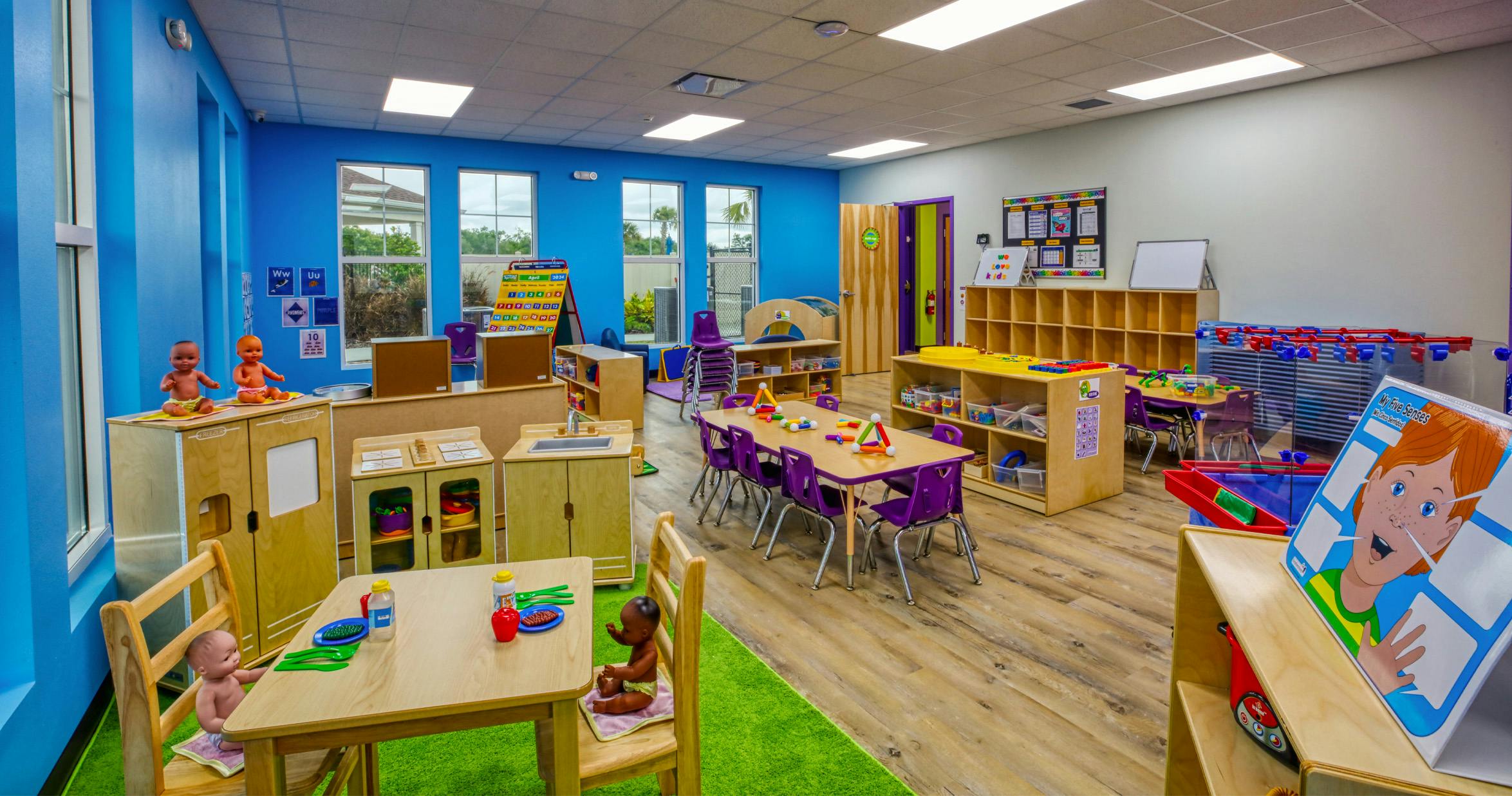 Classroom with child-sized furniture, play kitchen, and baby dolls