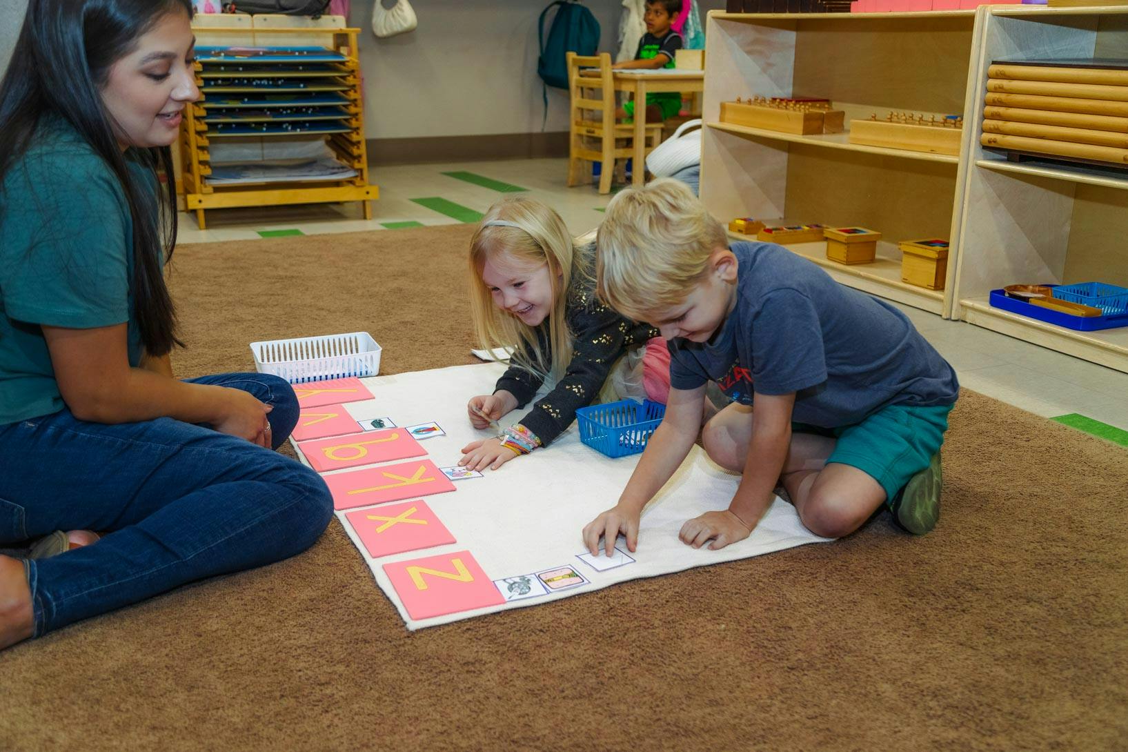 Person and two children on floor with learning materials