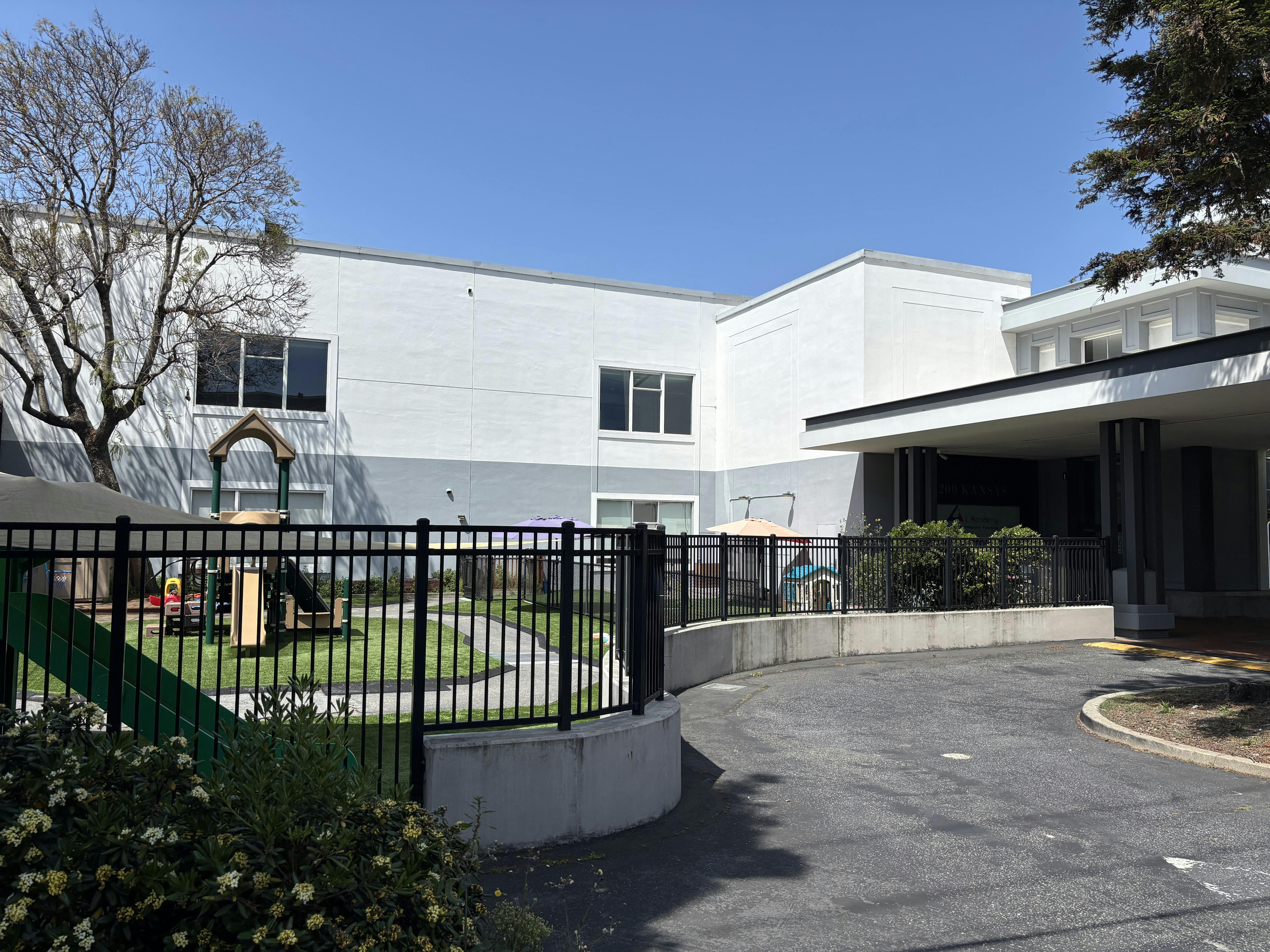 Building exterior with a fenced playground and paved driveway
