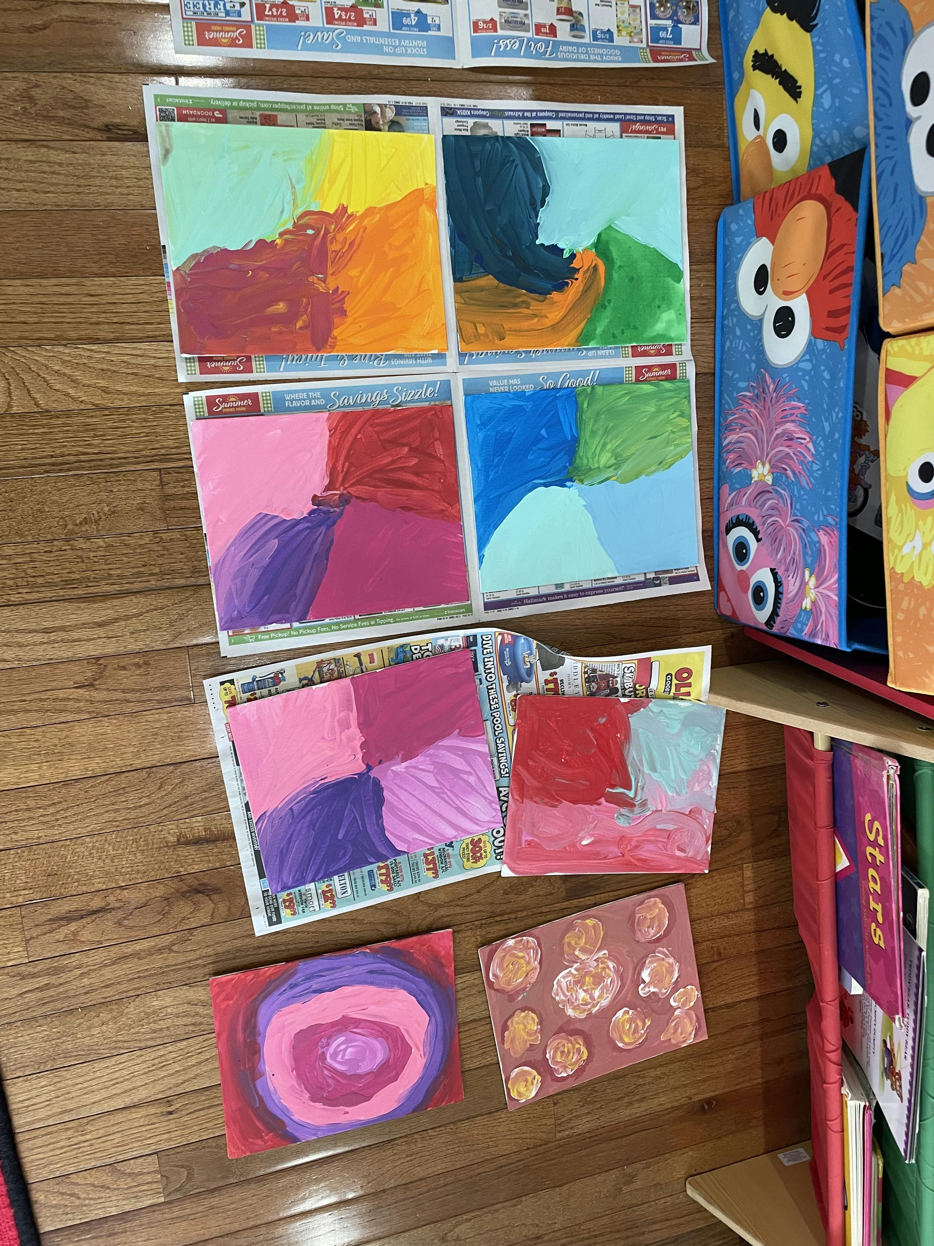 Multiple colorful abstract paintings on a wooden floor