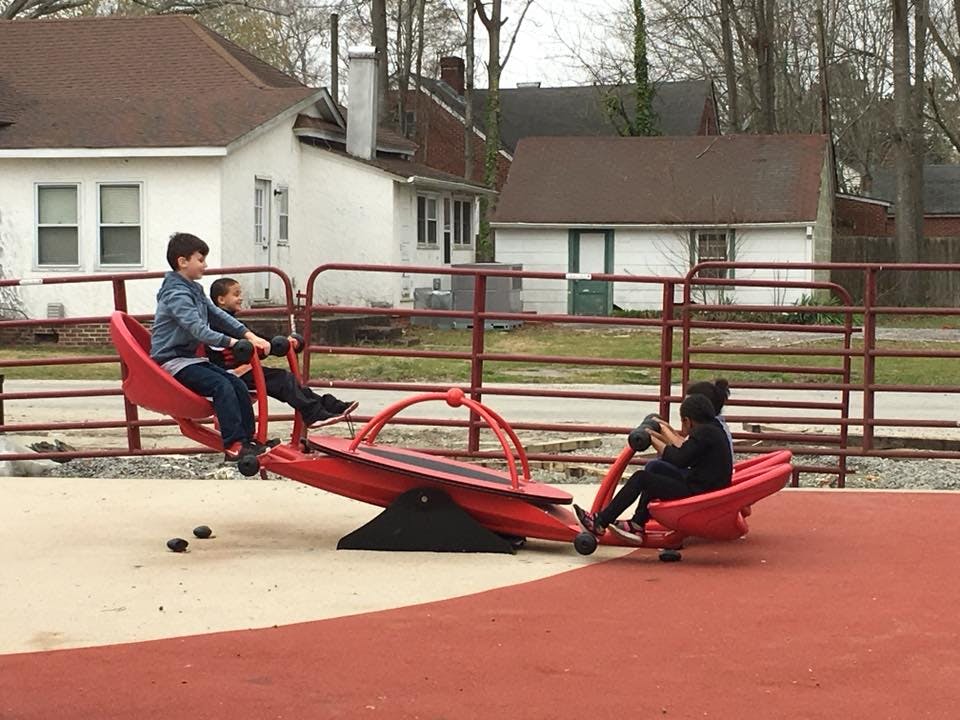 Three children on a red seesaw at a playground