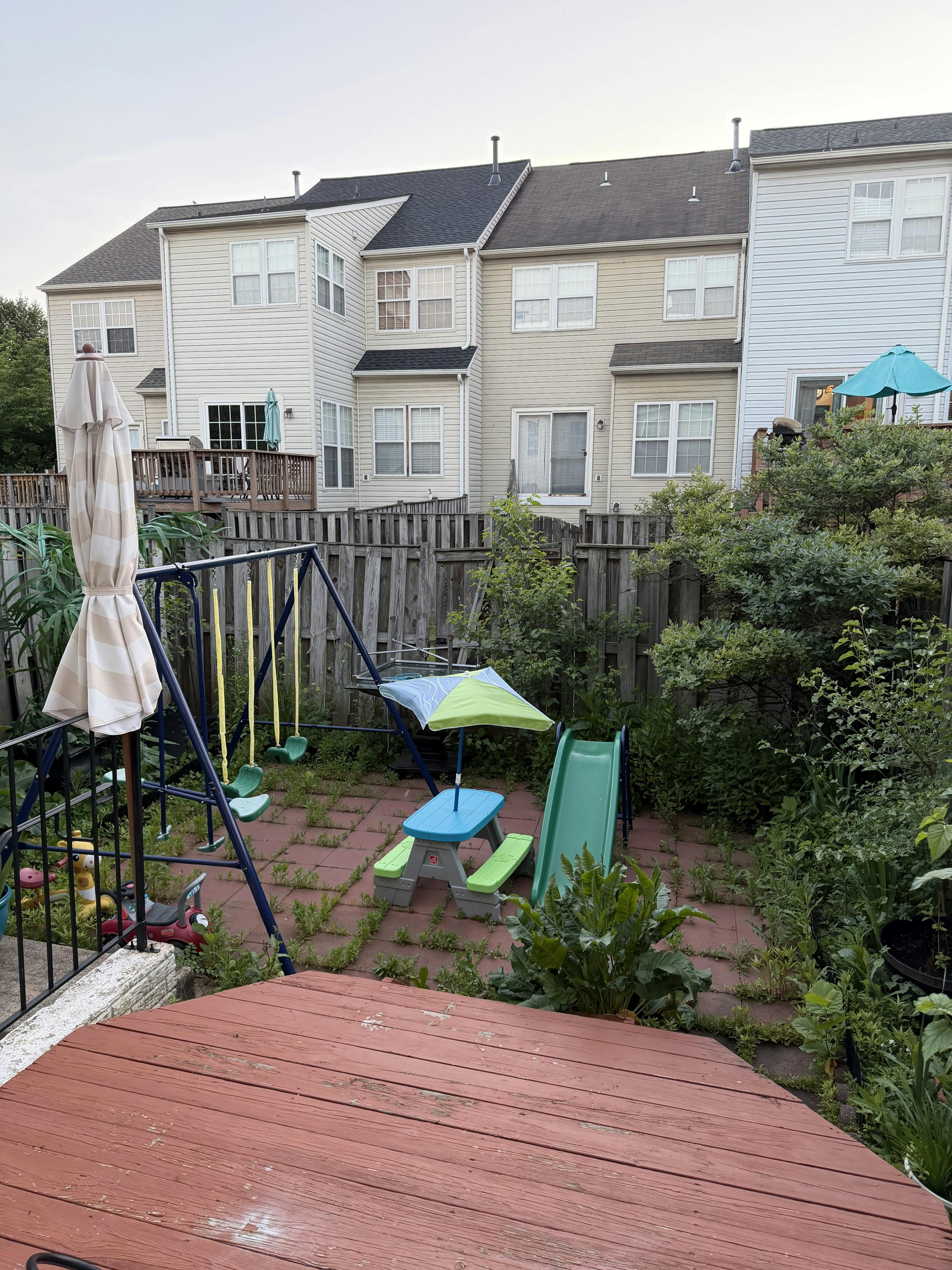 Backyard with a swing set, small picnic table with umbrella, and a slide