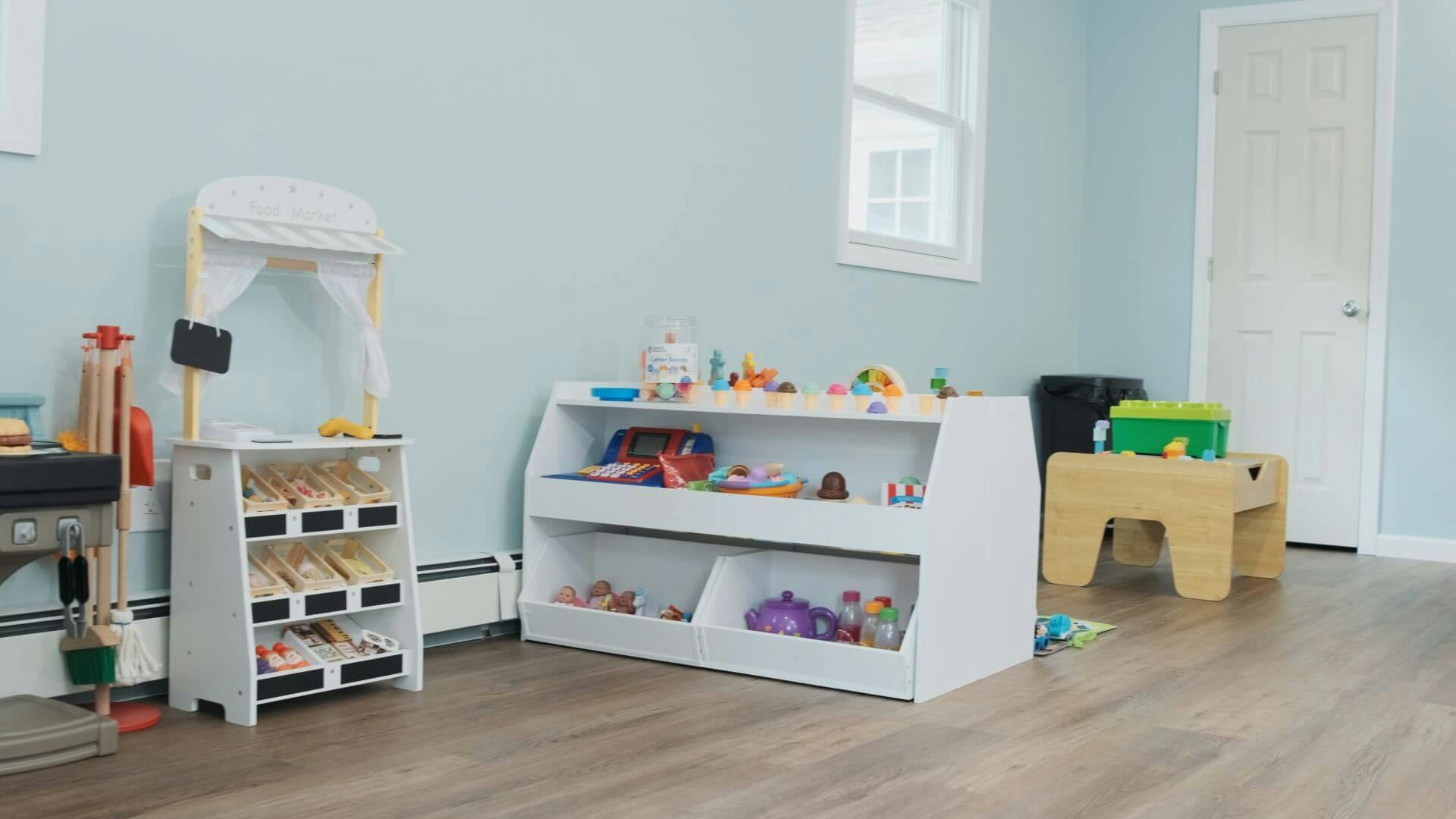 Playroom with toy food market stand and shelves filled with toys