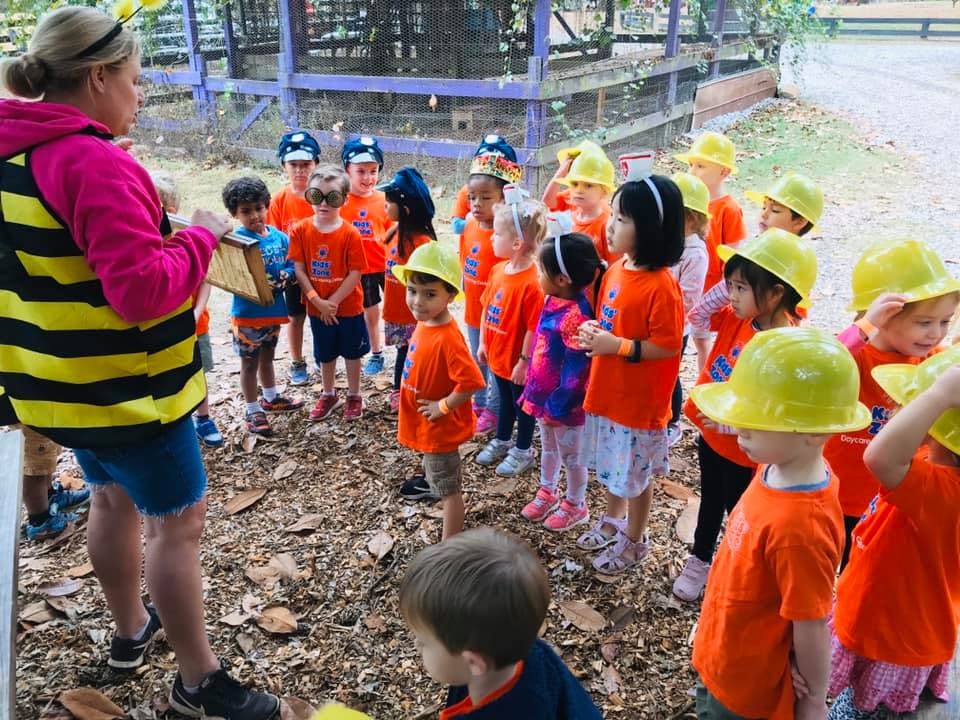 Person in bee costume teaching a group of children outdoors