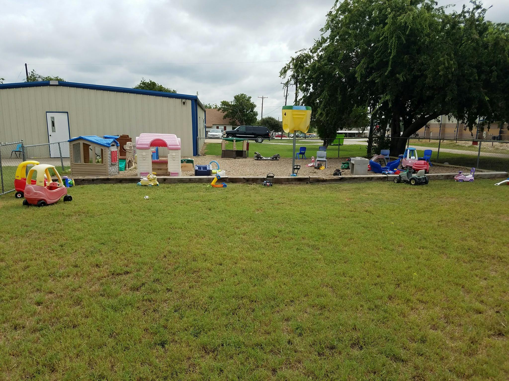 Outdoor play area with toy cars, playhouses, and sand