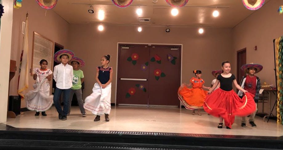 Children in traditional attire dancing on a stage