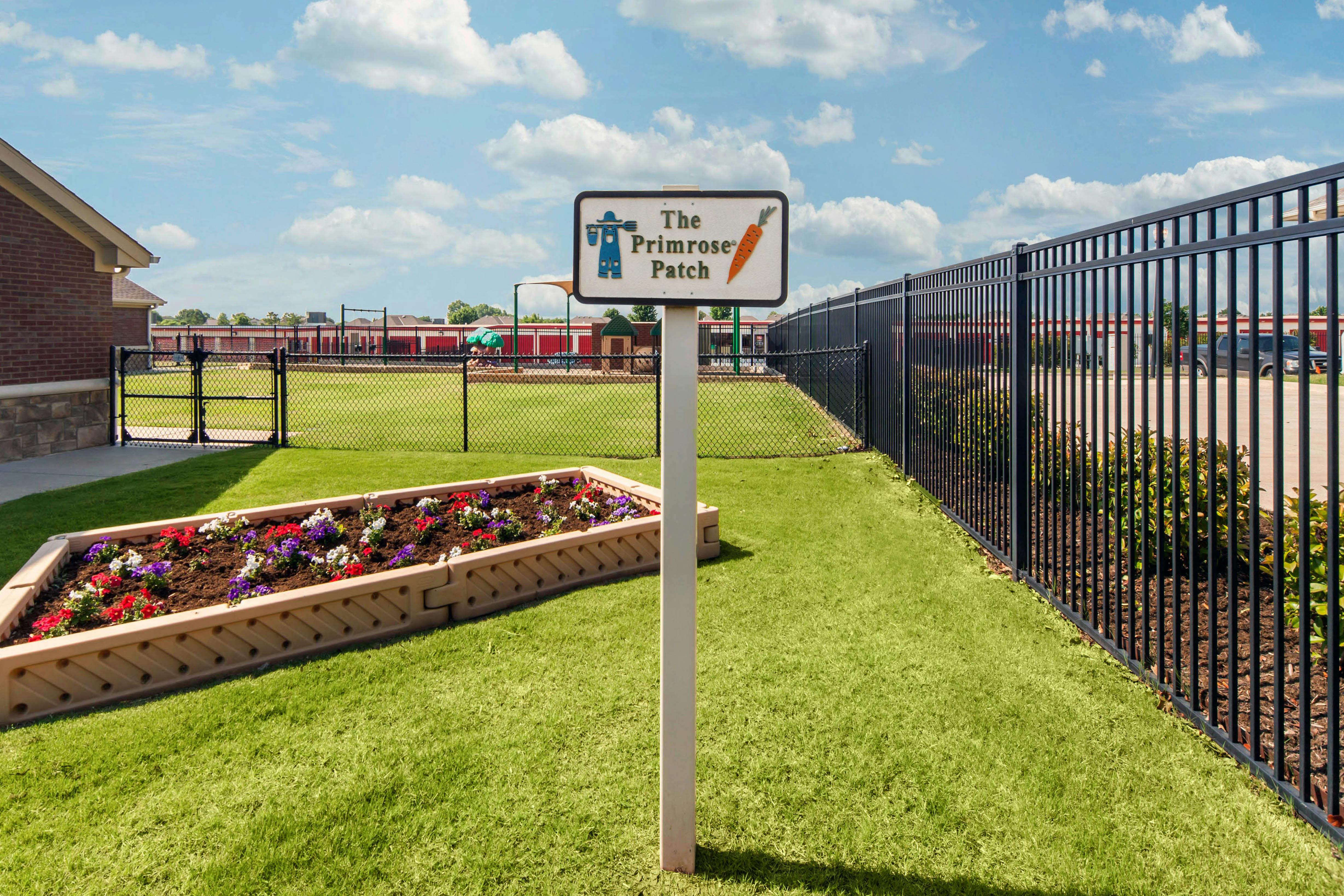 Sign that reads "The Primrose Patch" next to a raised garden bed with flowers