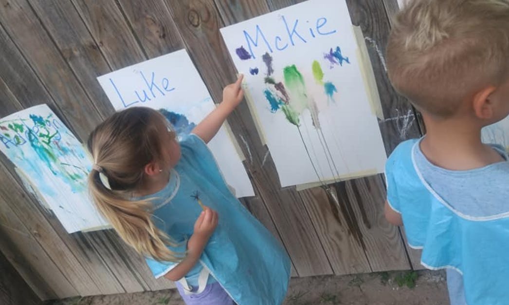 Child painting on paper with "MeKie" written on it