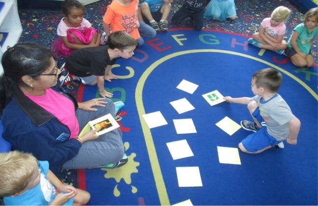 Person and children on a rug with letters and cards