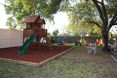 Backyard playground with a wooden playset, slide, and other play equipment