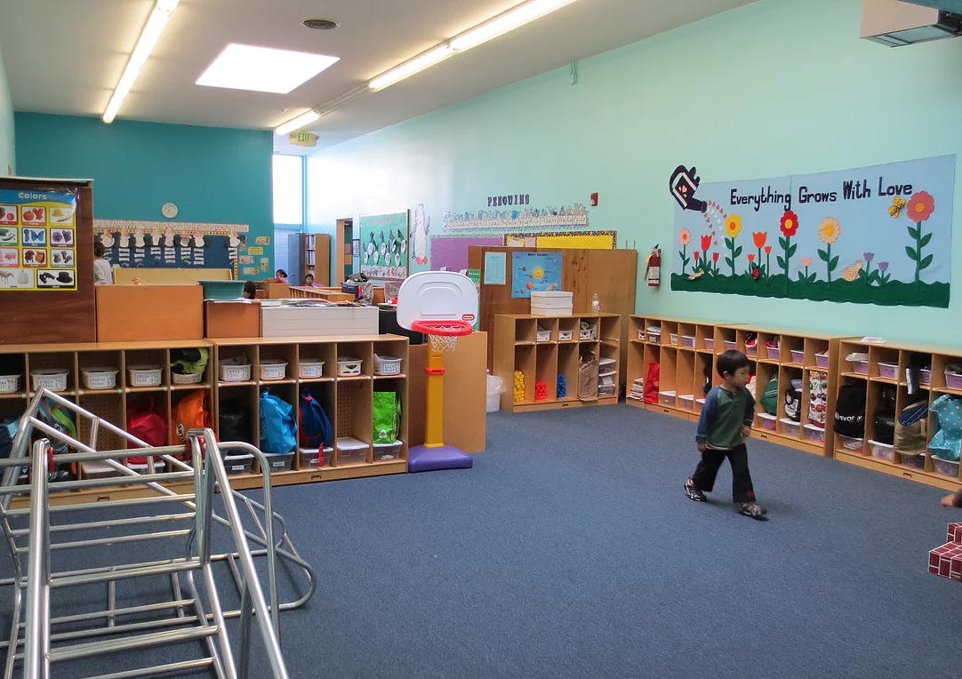 Child walking in a classroom with cubbies and play equipment