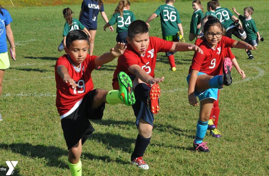 Children in soccer uniforms stretching on a field
