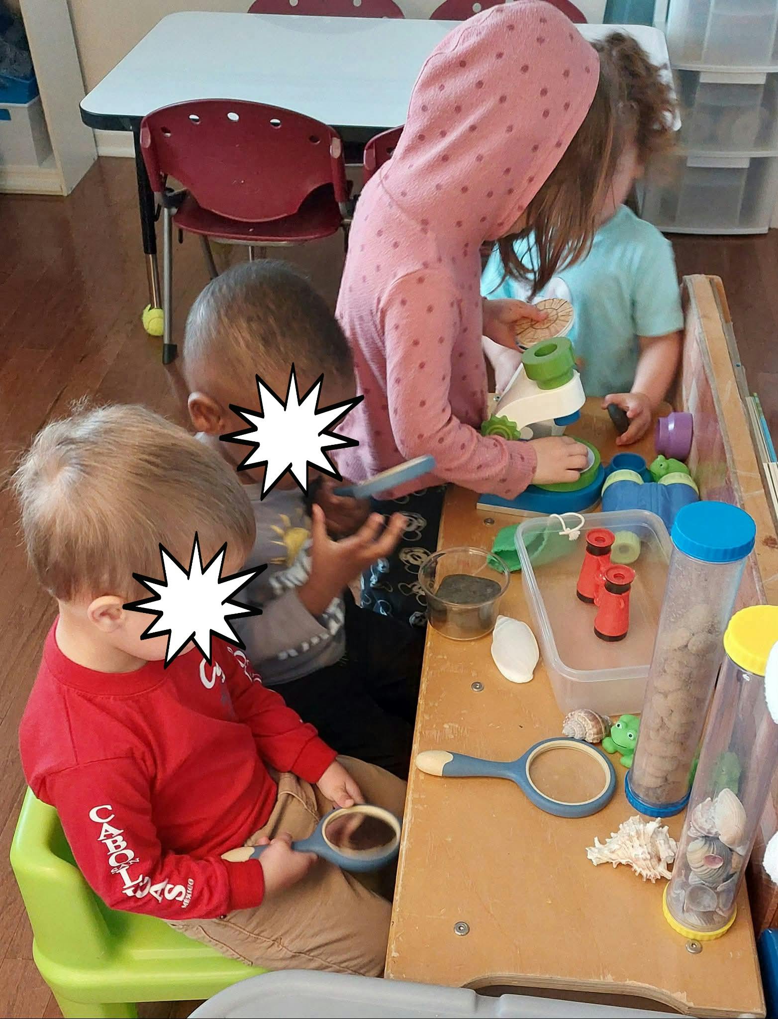 Children exploring items with magnifying glasses and a microscope