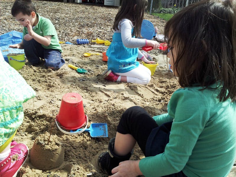 Children playing in a sandbox with toys