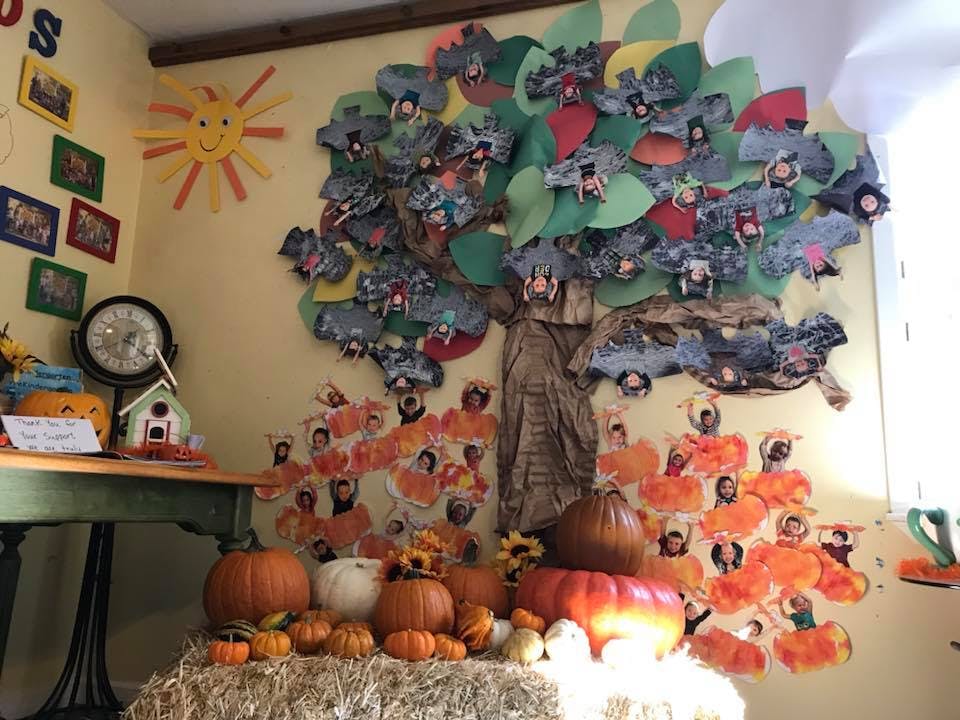 Classroom wall decorated with a paper tree, pumpkins, and student artwork
