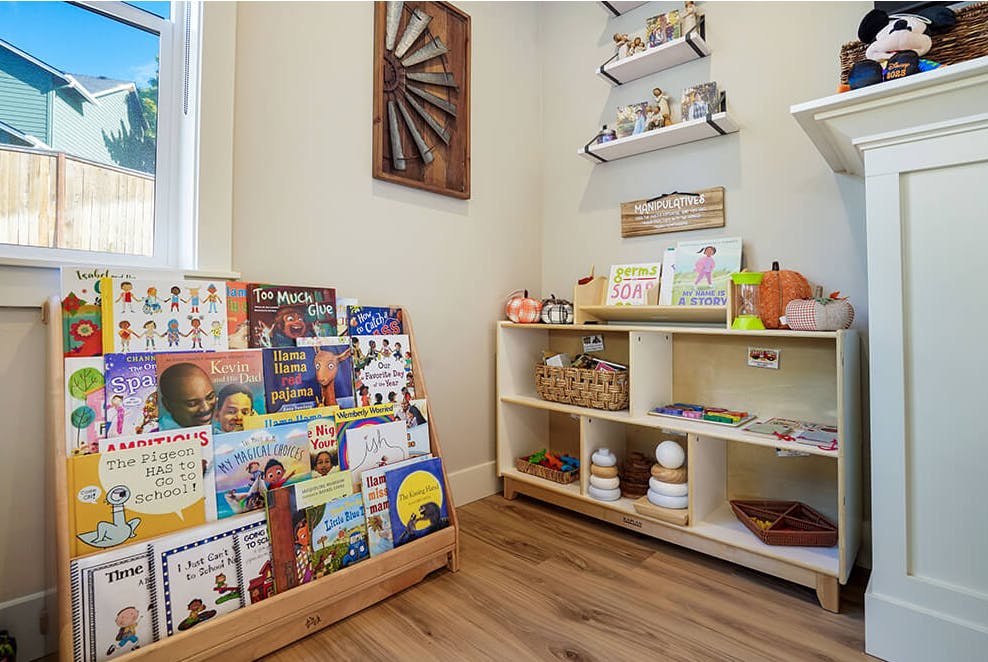 Children's books on a low shelf next to a classroom organizer with manipulative toys