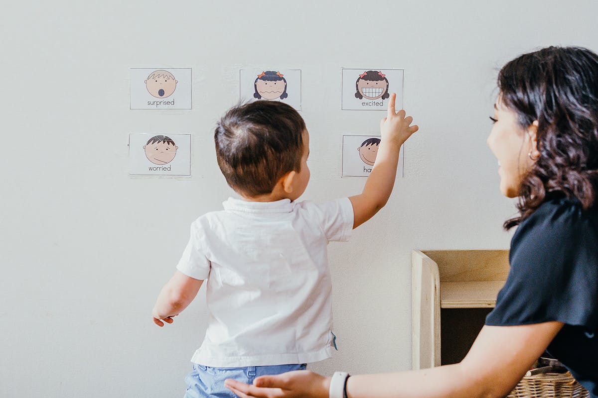 Child pointing at a picture on a wall with a person watching