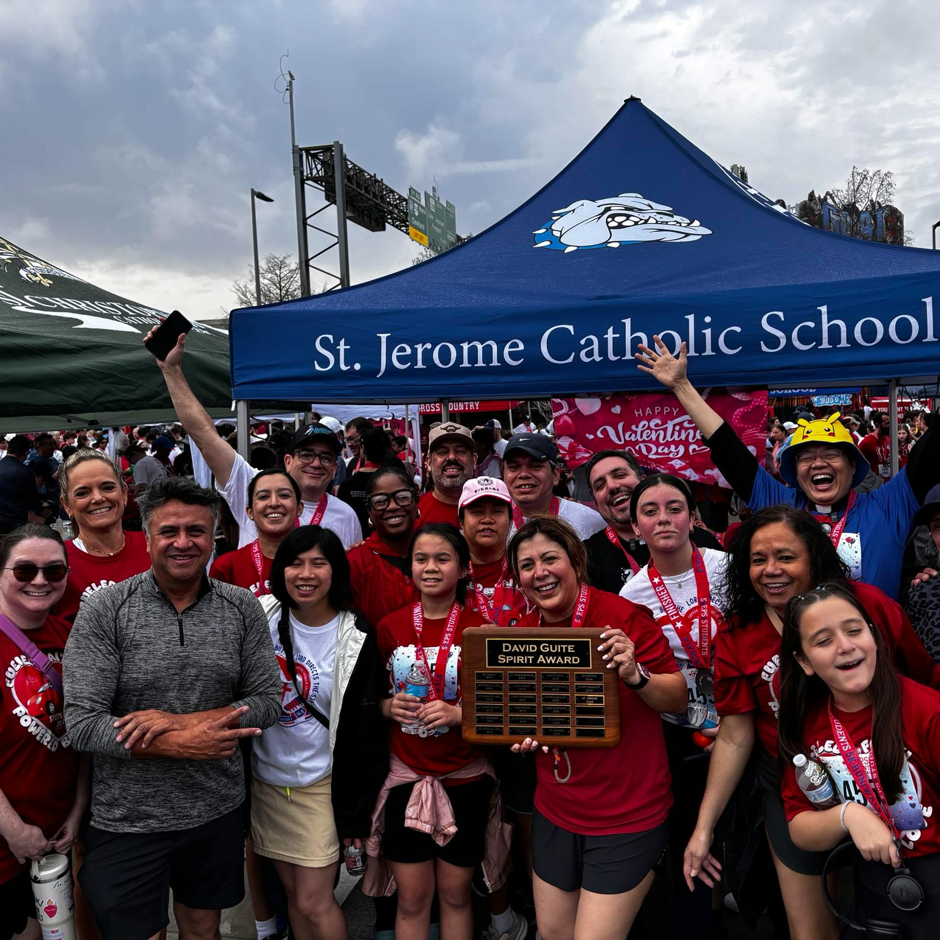 Group of people under a St Jerome Catholic School tent holding a David Guite Spirit Award
