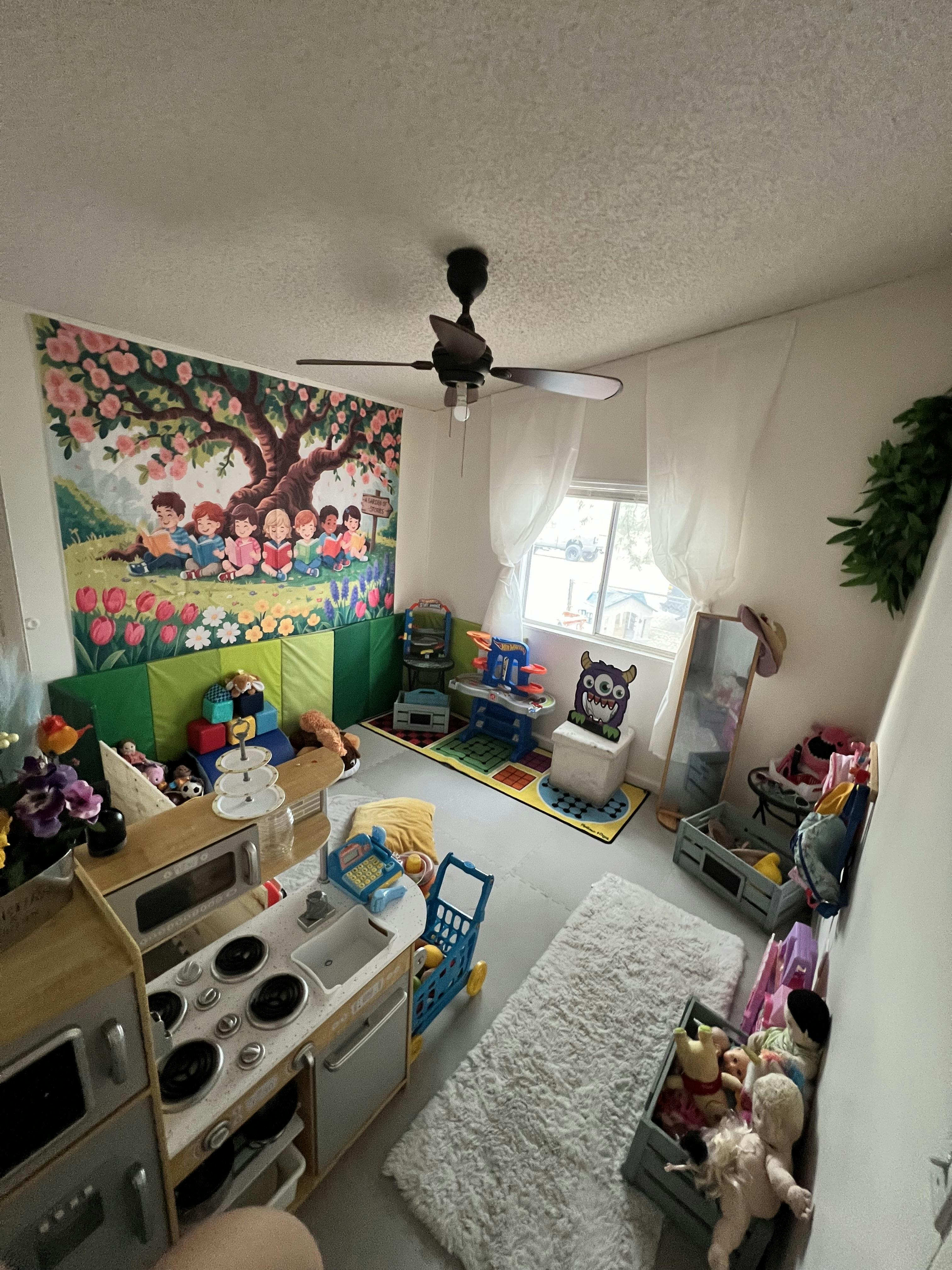 Playroom with a children's kitchen set and a large wall mural of reading children
