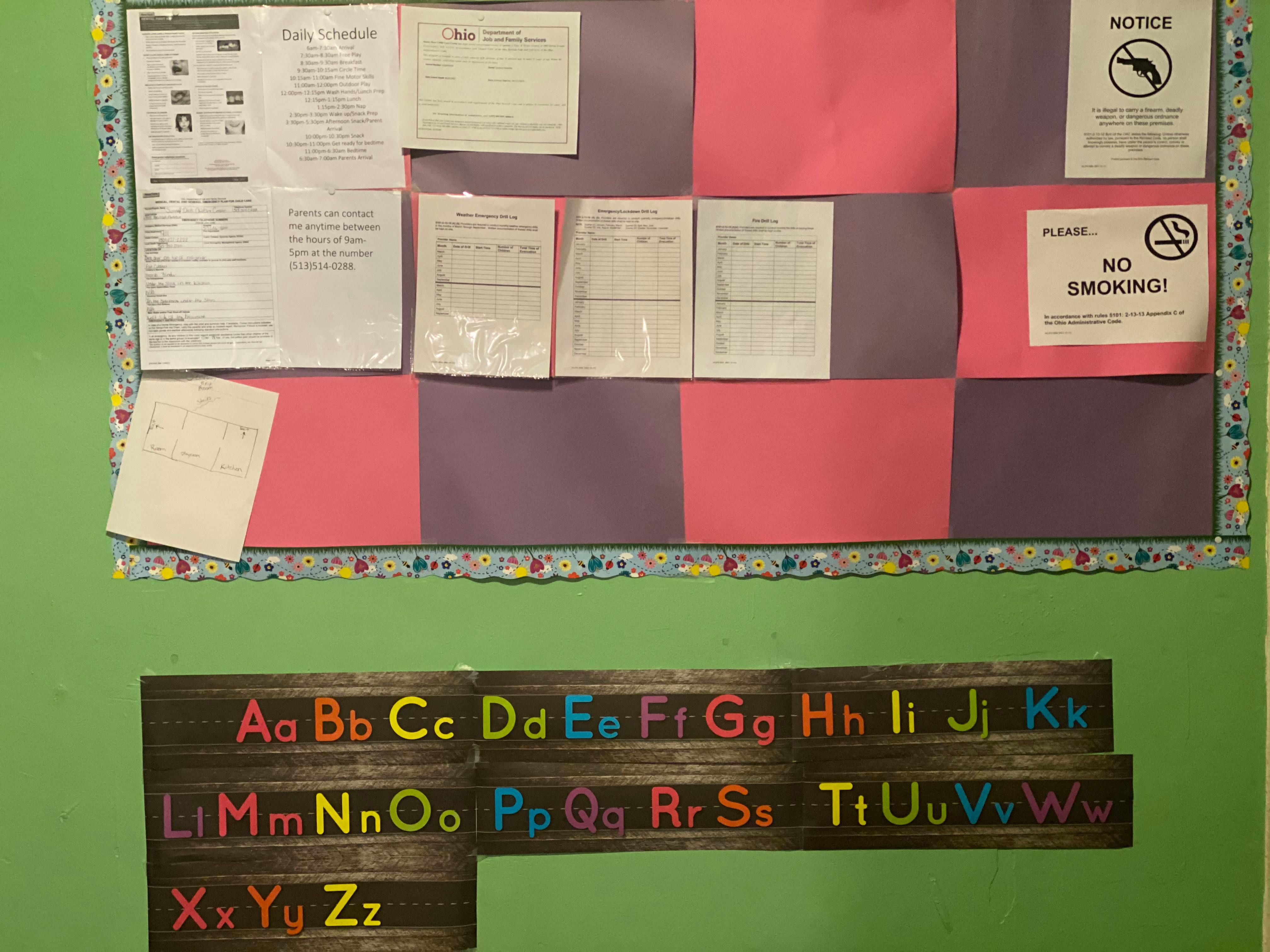Bulletin board with papers and a sign that says "NO SMOKING" above an alphabet chart