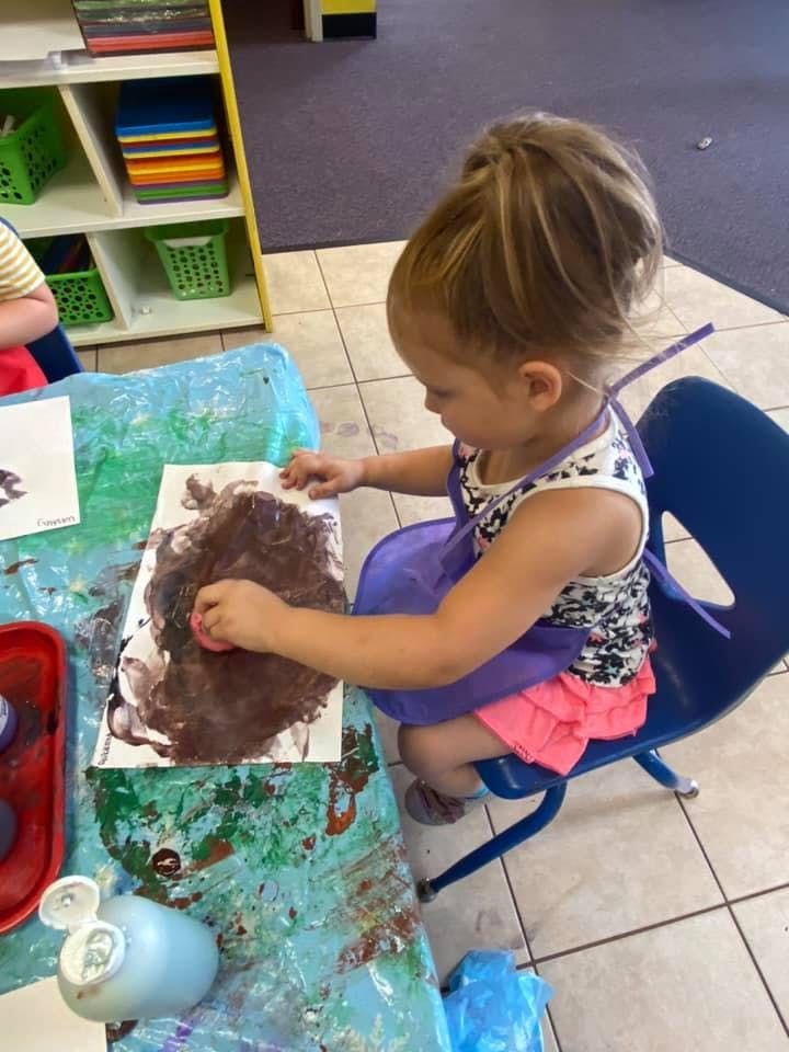 Child painting with a sponge at a table