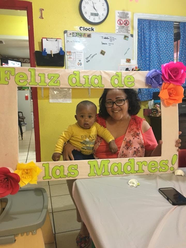 Person holding a child, both smiling through a decorative frame with text