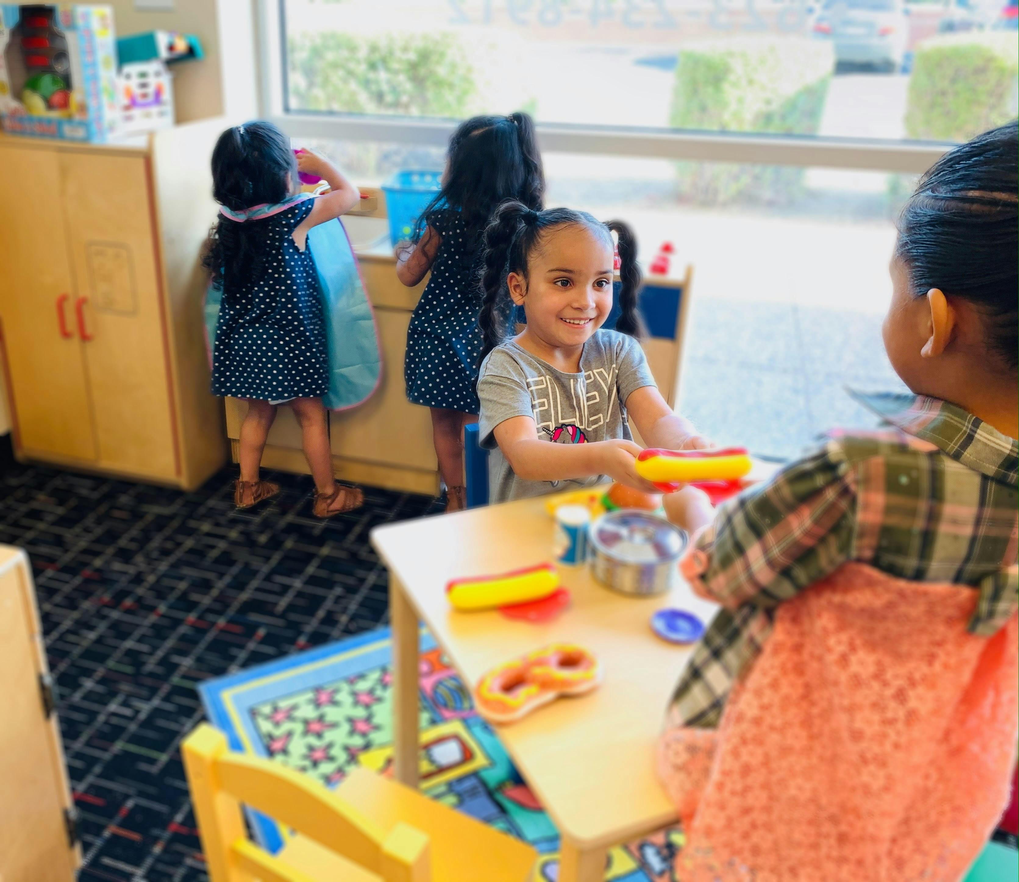 Child playing with toy food at a table in a classroom