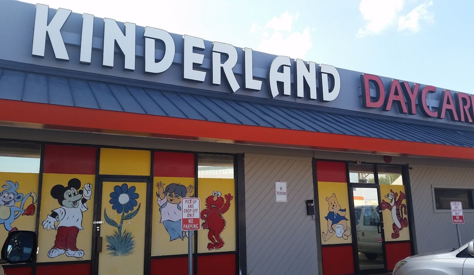 Kinderland Daycare sign above building entrance with cartoon window decals