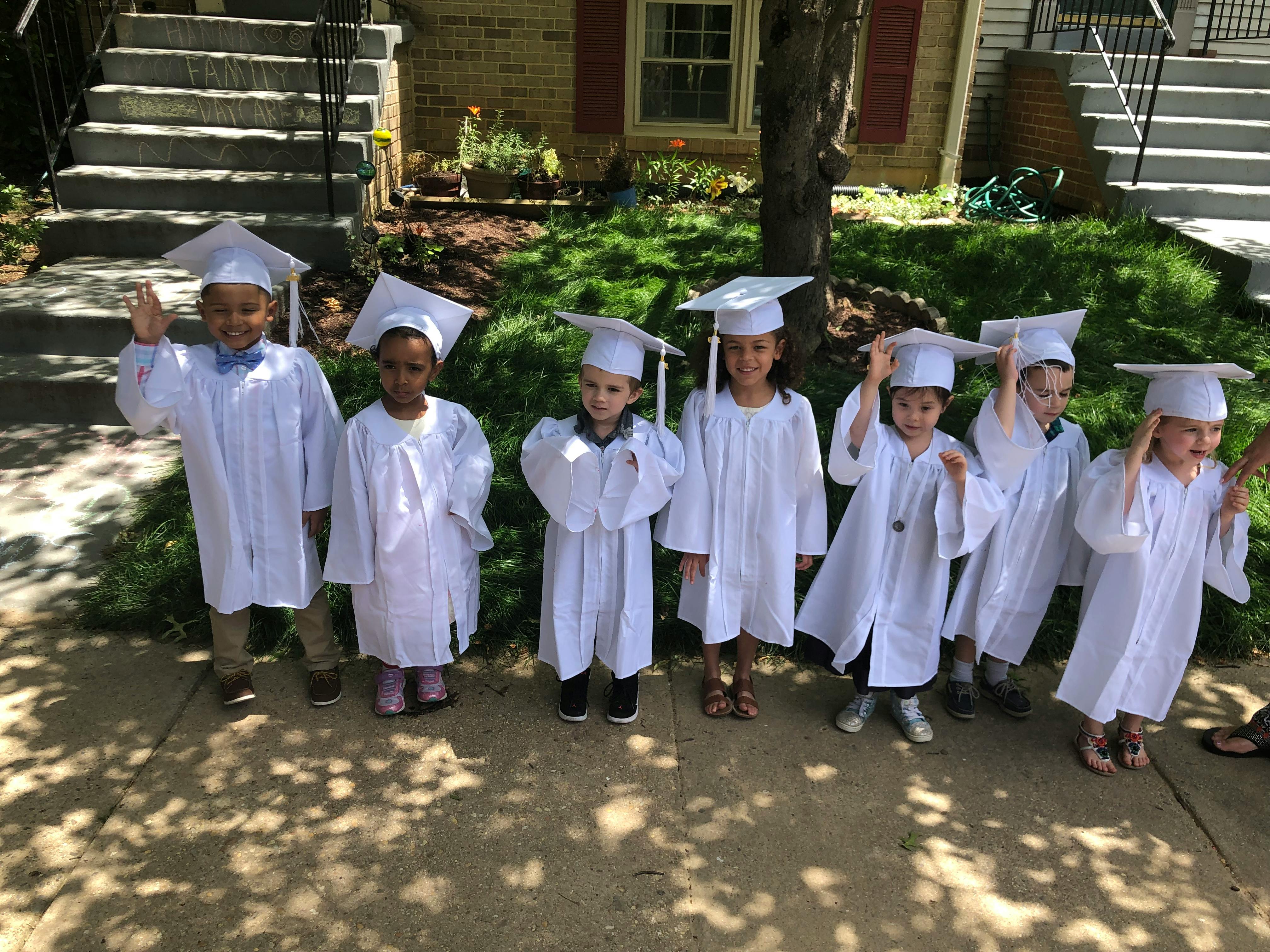 Group of children in white graduation caps and gowns