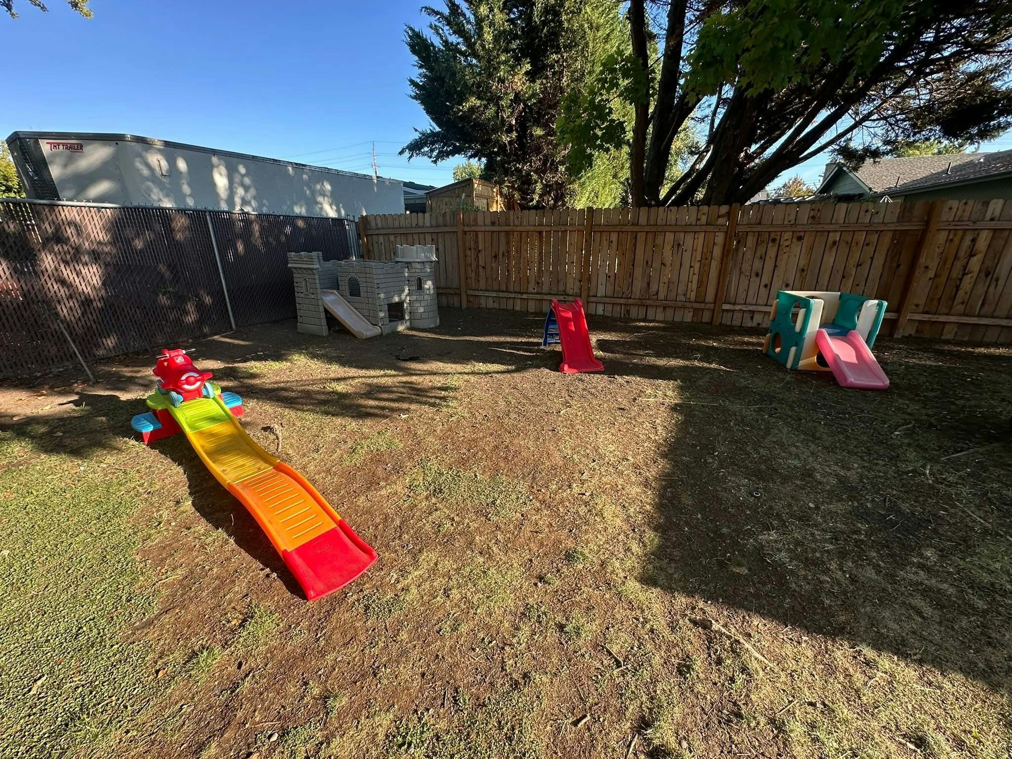 Three colorful plastic slides in a grassy backyard