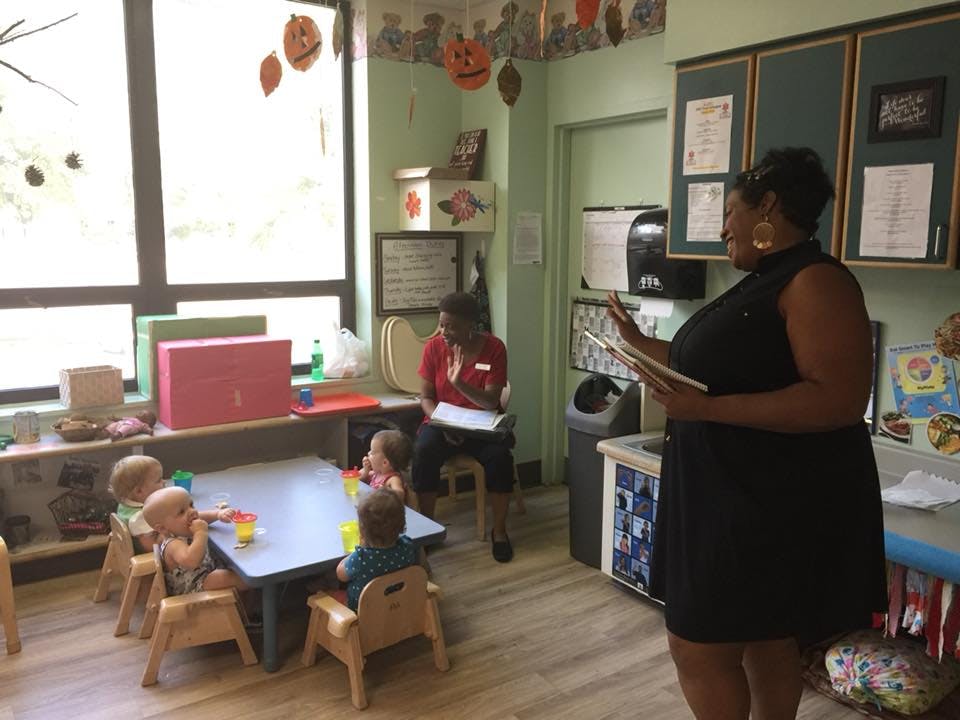 Adult reading to children at a table in a classroom