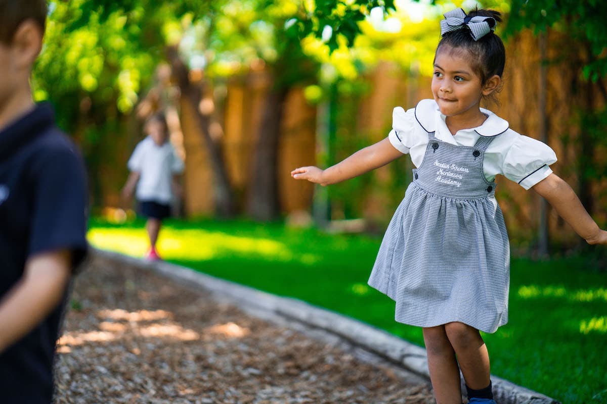 Child in a dress balancing on a curb outdoors