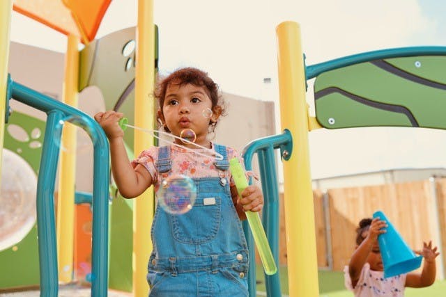 Child blowing bubbles on a playground