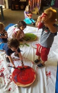 Children painting on a drop cloth
