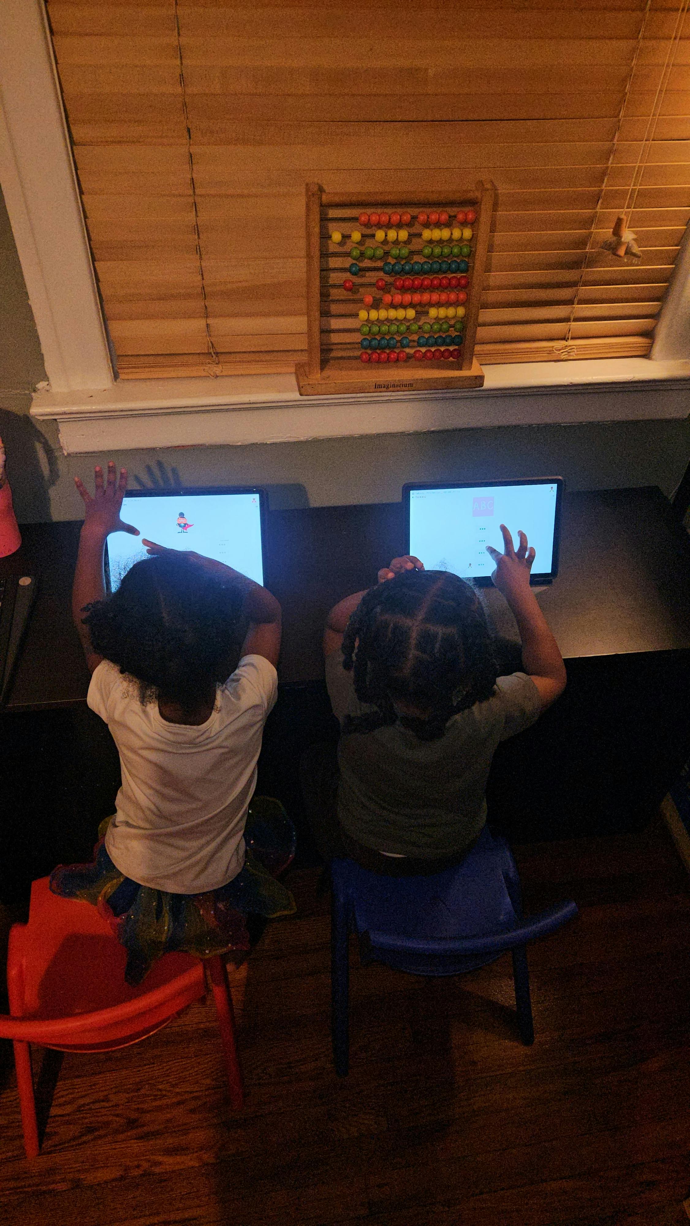 Two children using tablets at a table