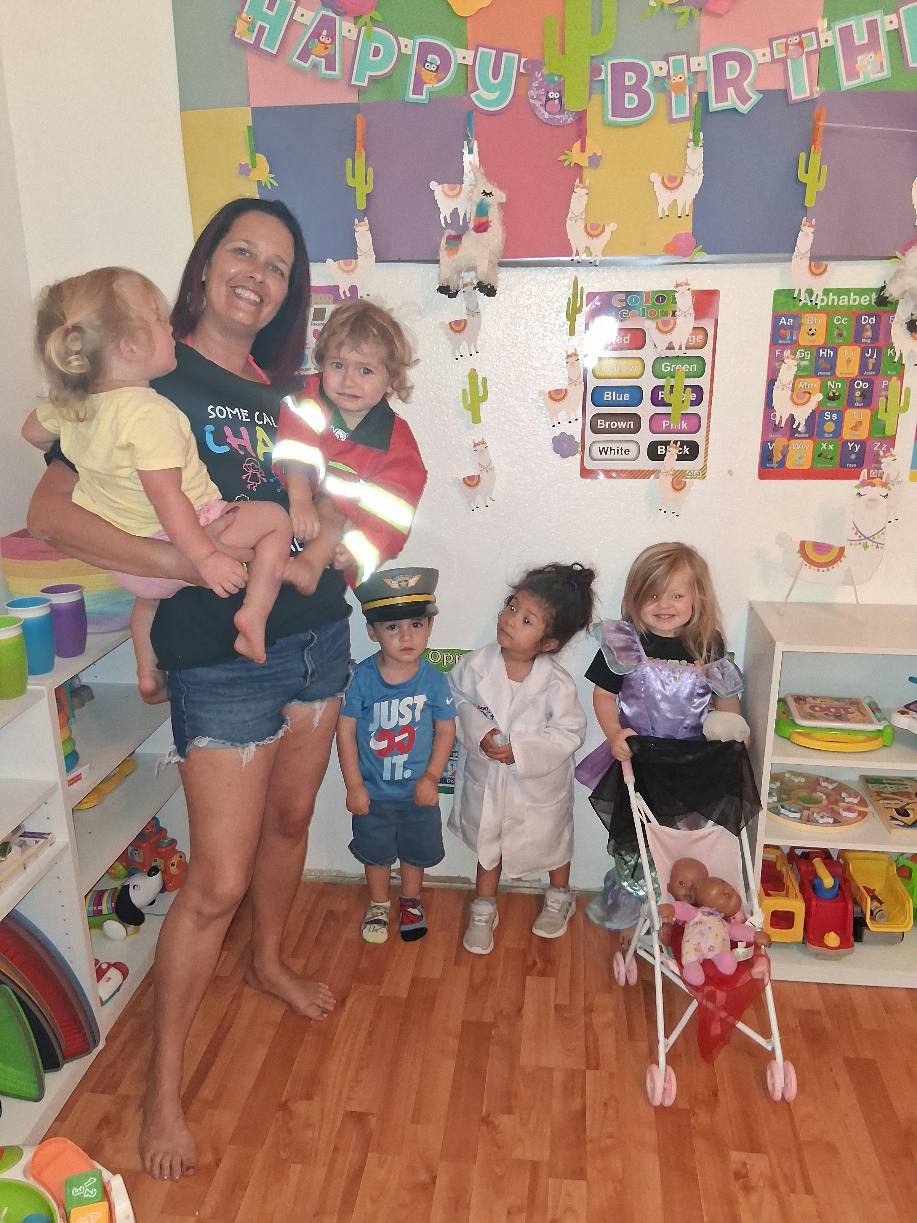 A person holding a child among several children dressed in costumes in a playroom