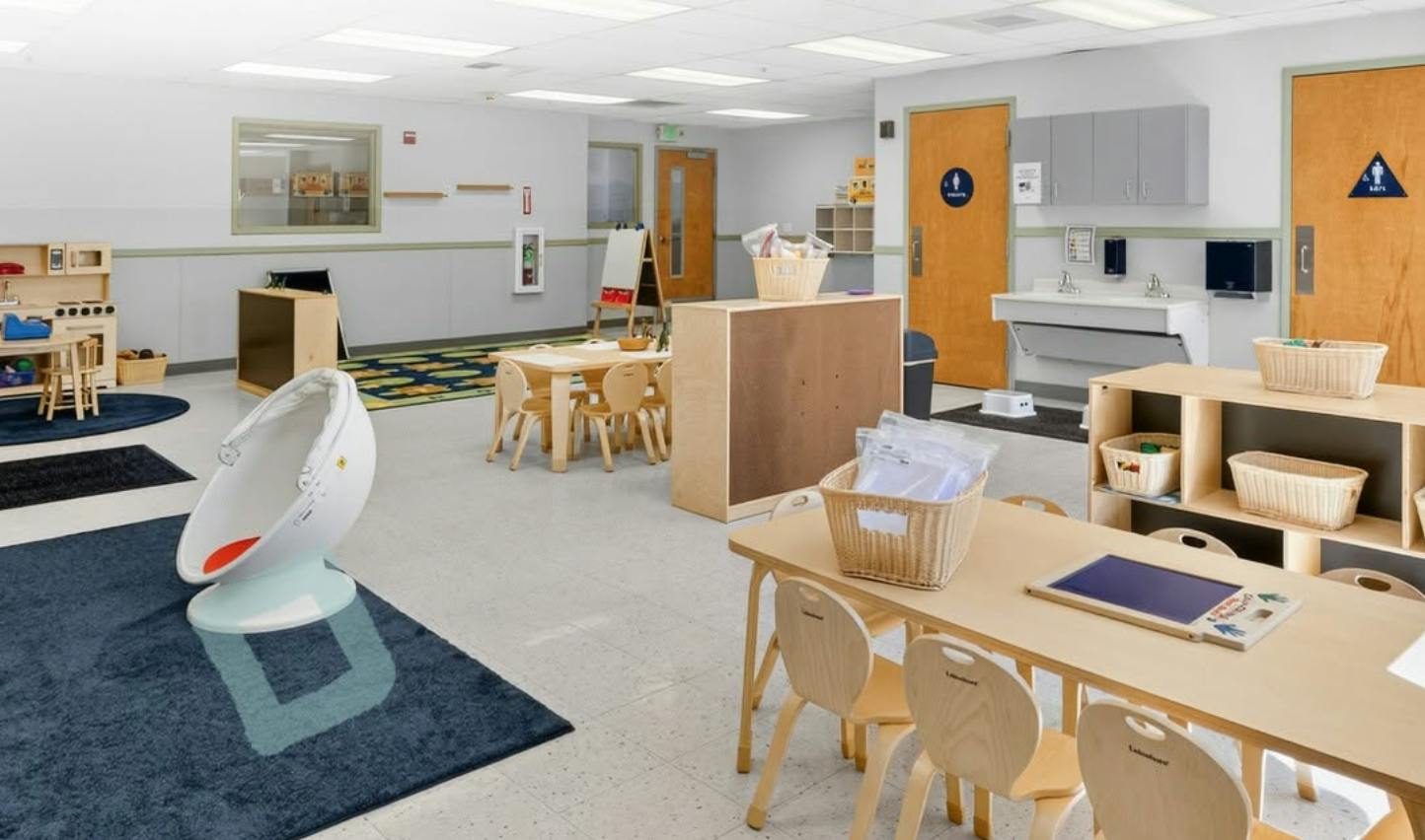 Classroom interior with small tables, chairs, and play areas