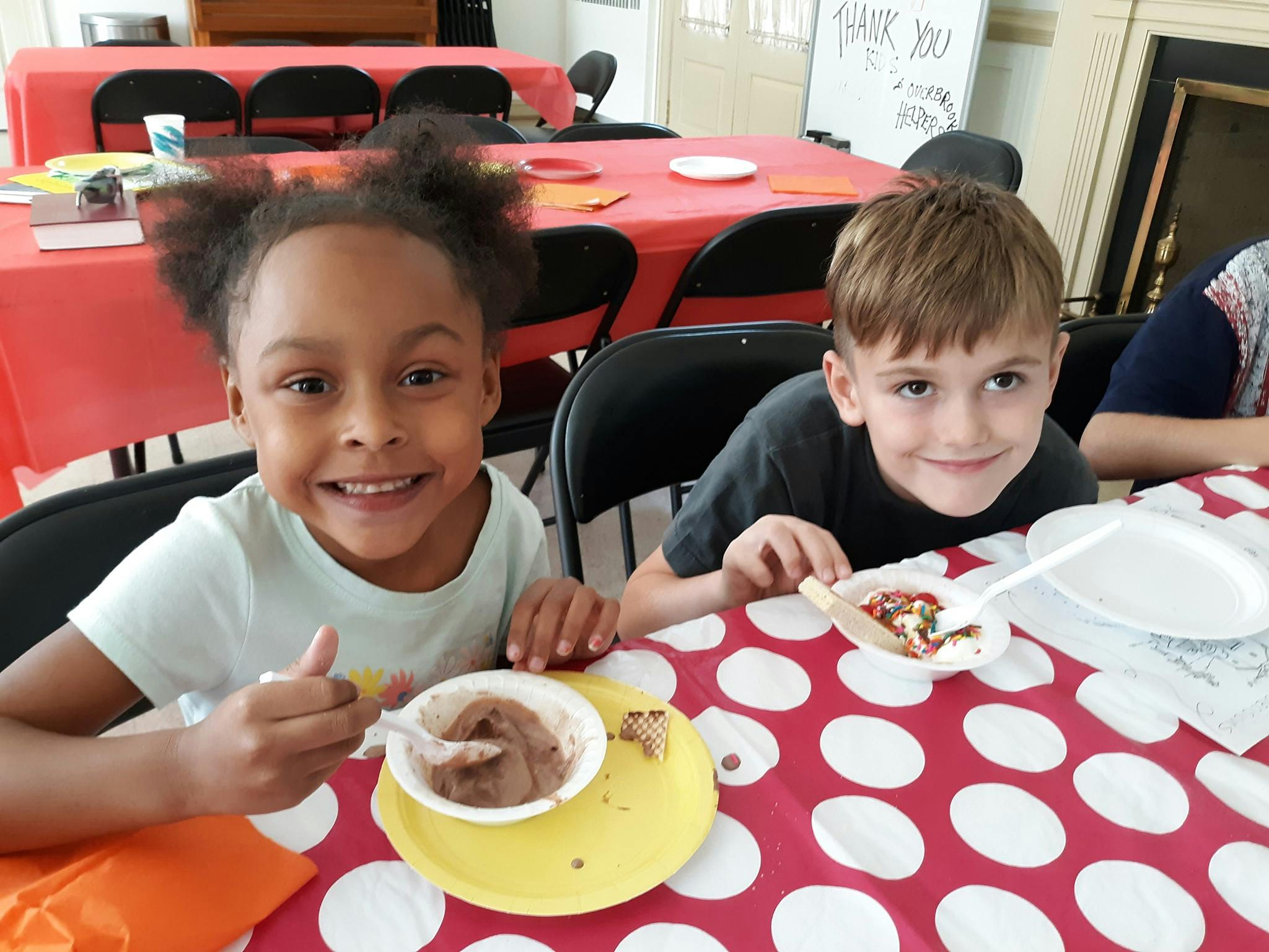 Two children sitting at a table with dessert