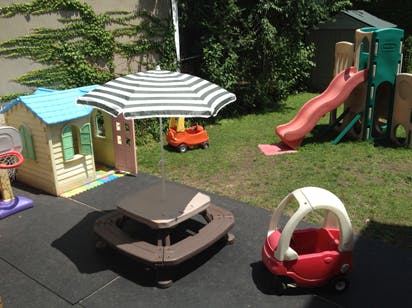 Playground with a small house, picnic table, umbrella, and slide