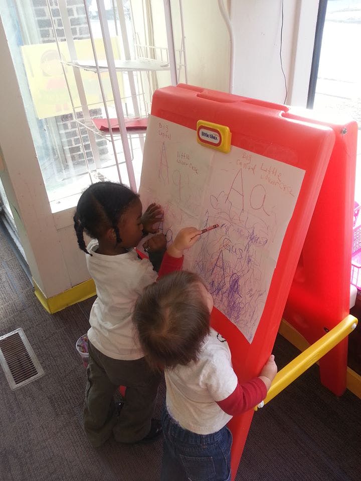 Two children drawing on an easel